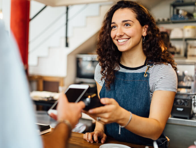 Woman holding out a payment processor to someone holding a smartphone